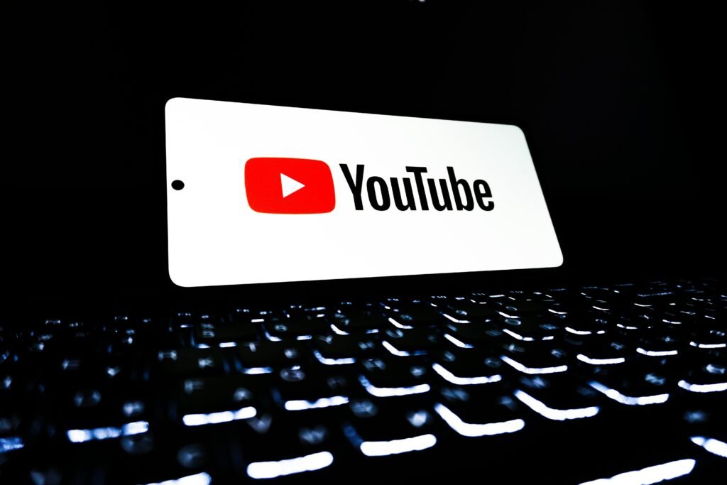 pexels photo 33440447 33440447 YouTube app icon displayed on a smartphone over an illuminated keyboard, representing digital media and online streaming.