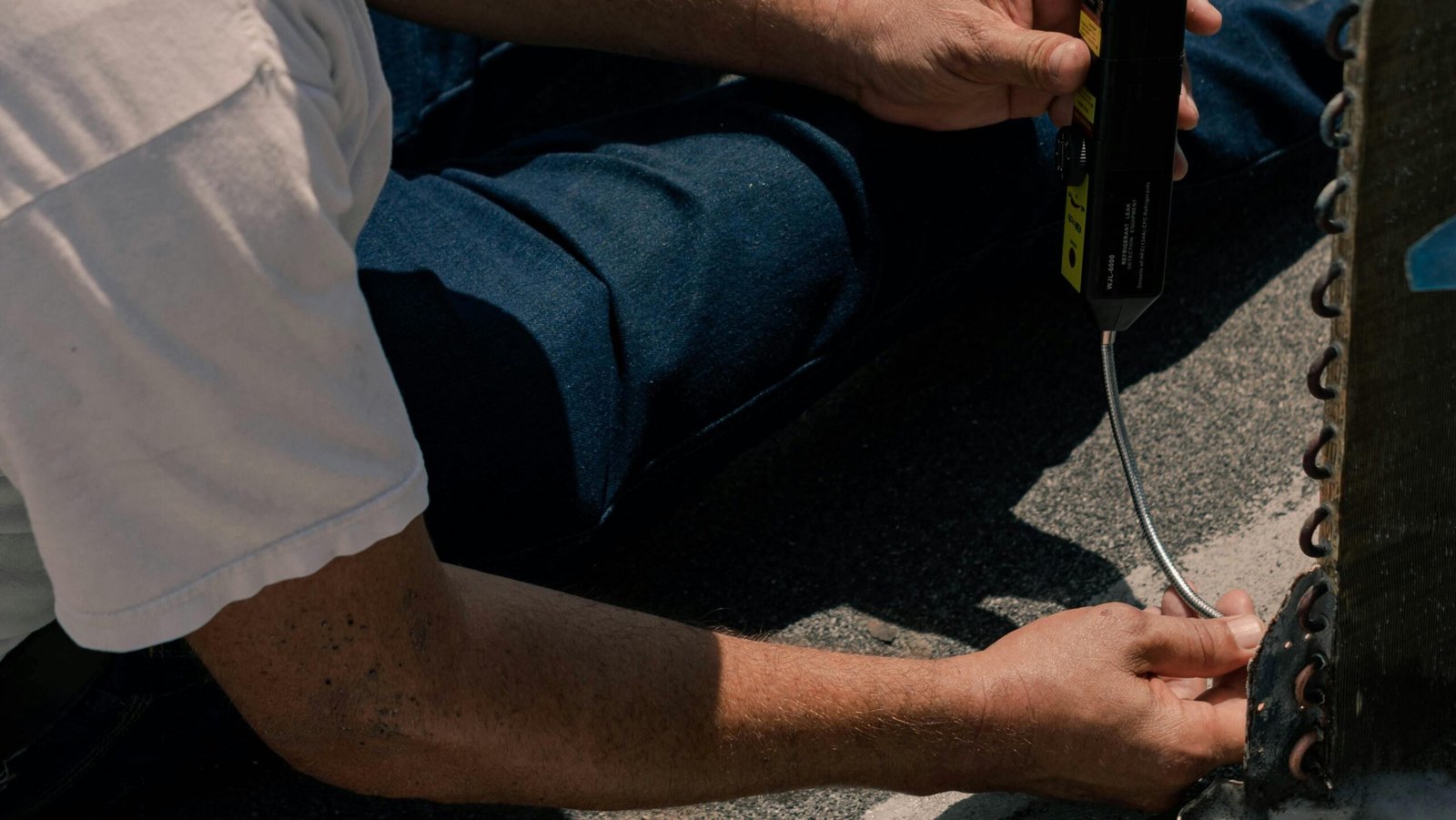 Manual laborer repairing air conditioning unit outdoors in Cancún.