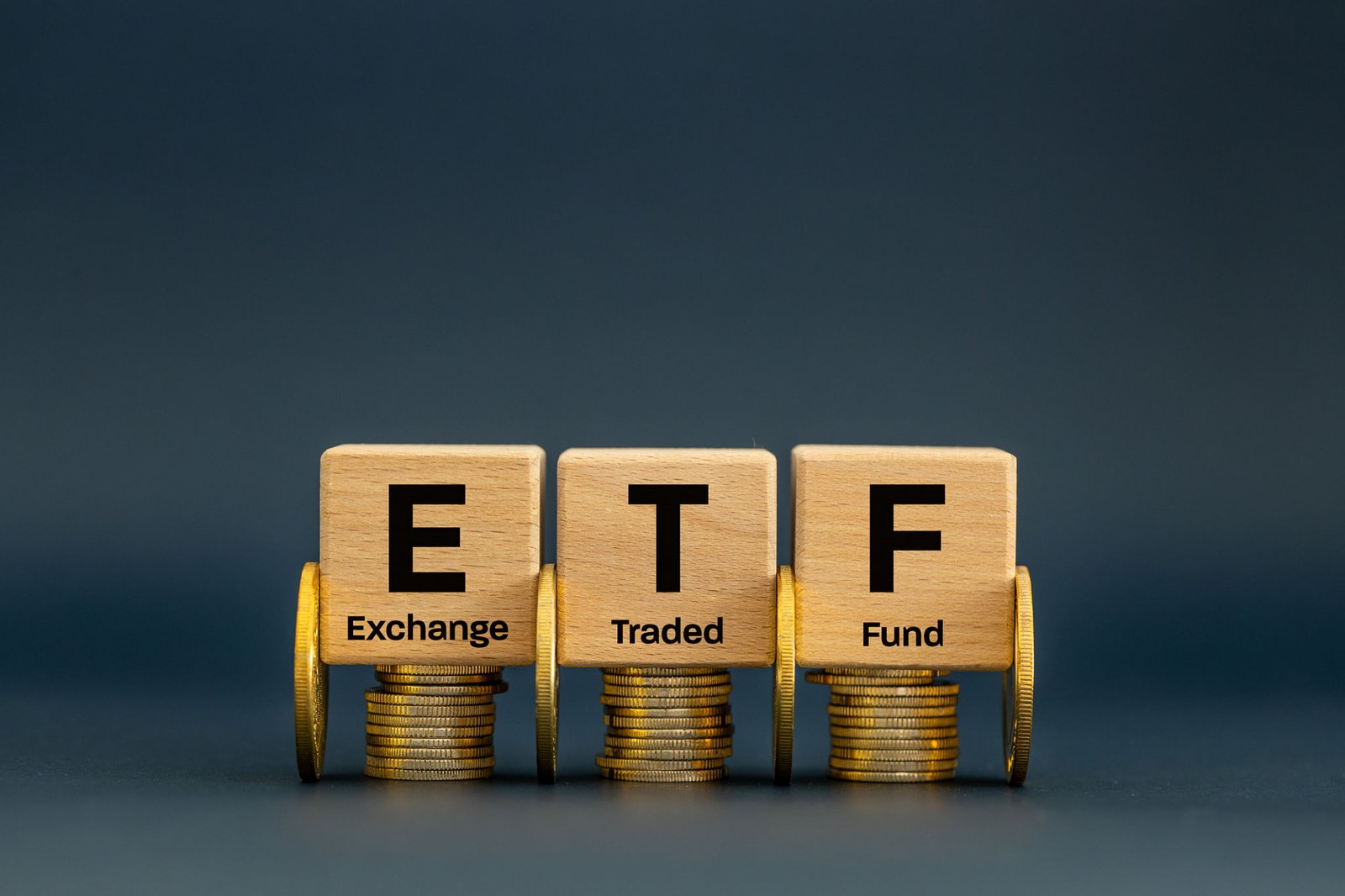 Symbol ETF, skrÃ³t od Exchange Traded Fund, koncepcja biznesowo-finansowa. Wooden cubes with ETF icon on a navy blue background. A stock market index fund in the financial sector for business stocks.
